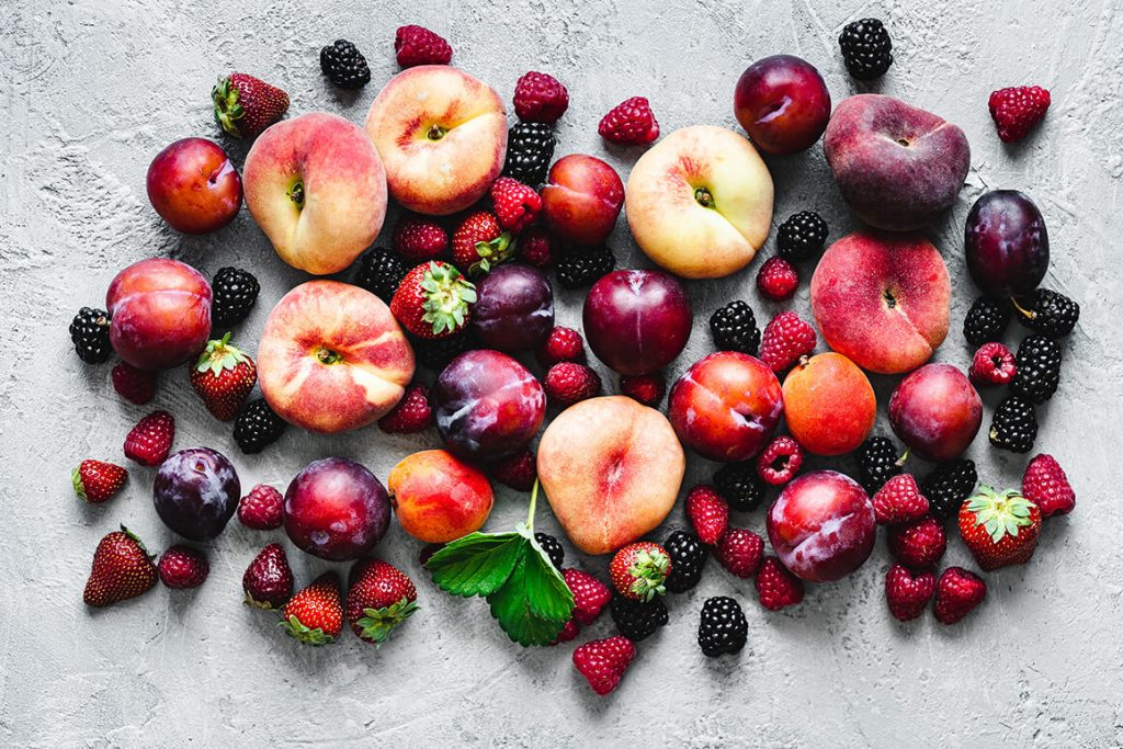 Viele verschiedene Obstsorten liegen in Form eines Herzes auf einem Tisch.